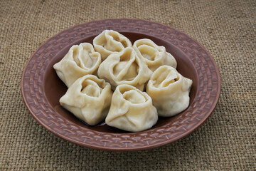Dumplings in a brown plate on burlap
