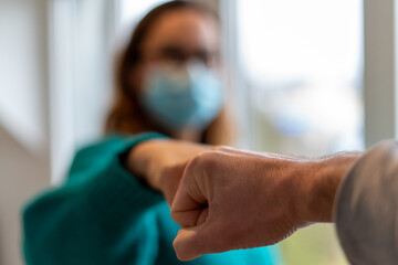salutation avec le poing fermé au temps du coronavirus et de la distanciation sociale entre une femme portant un masque bleu et un homme © Fred