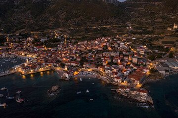 Aerial drone shot of Komiza town port in night with city light on Vis Island in Croatia summer dusk