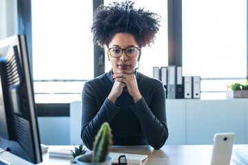 Beautiful afro business woman relaxing while looking at camera in the office.