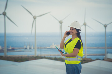 adult female engineer supervises solar panels and windmills in a renewable energy complex