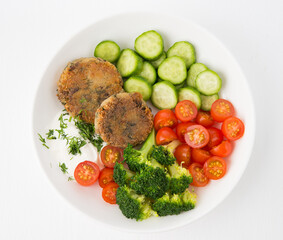 Vegetarian dish of potato patties with herbs and vegetables in a plate