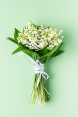 Lily of the valley flowers on a pastel green background. Womens Day, Mothers Day, Wedding concept. vertical shot
