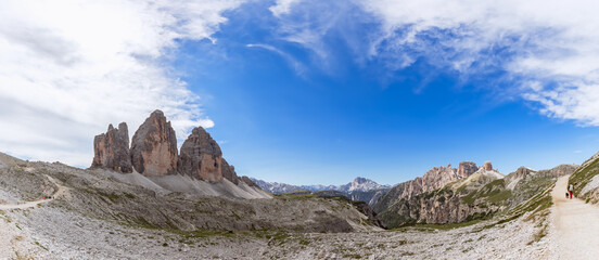 Beautiful panorama of Tre Cime di Lavaredo and tourist with his dog walking along the trail