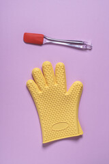 Silicone kitchen spatula and heat resistant glove on pink background. Abstract cooking concept. Flat lay, top view with copy space