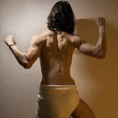 Long haired male model flexing muscles, defined back and arm muscle anatomy for artists