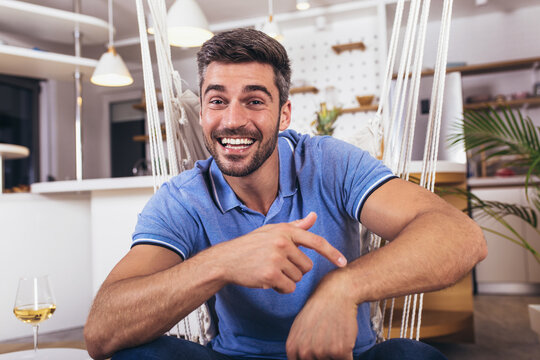 Image of a positive smiling young man indoors at home looking camera.
