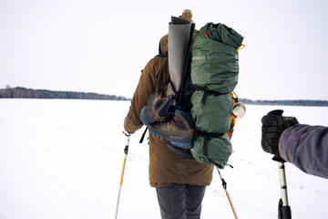 Fototapeta na wymiar A guy with a big backpack walks in the snow during a winter hike