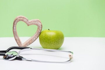 Apple, heart and stethoscope on horizontal green and white background