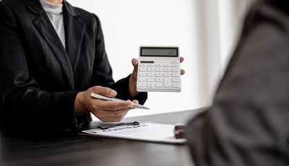 A car rental company employee holds a white calculator to show the tenant the rental price, the...