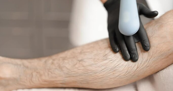 Doctor doing targeted magnetic therapy on male leg at the clinic. Physiotherapeutic therapy with recovery effect of muscle tissue after injury