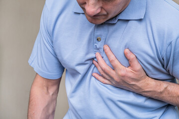 Heart pain, a person grabbing the heart area with his hand, suffering from chest pain, having a...