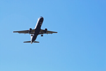 Fototapeta na wymiar Avión Airbus visto desde abajo en la maniobra de aterrizaje. Avión acercándose a la pista del aeropuerto Madrid-Barajas Adolfo Suárez.