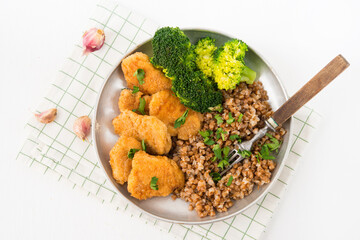 Homemade chicken nuggets with buckwheat and vegetables in a plate