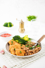 Homemade chicken nuggets with buckwheat and vegetables in a plate