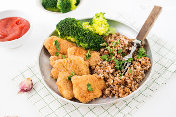 Homemade chicken nuggets with buckwheat and vegetables in a plate