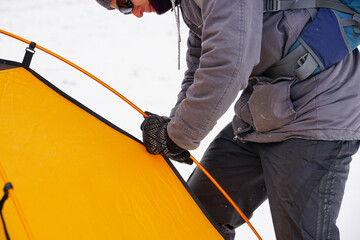 Two guys are setting up a tent in the snow. Setting up a tent during a winter expedition in extreme conditions. Winter trekking