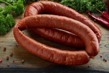 Sausage lies with spices on a wooden background