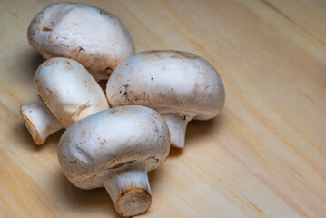 big delicious champignons are cut at the root and lie on a wooden board, ready to cook