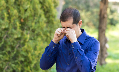 Disgusted man rubbing his eyes in a nature