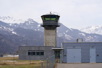 Flight control tower of military airbase with snow mountain panorama in the background. Photo taken...