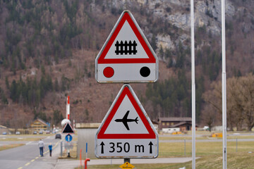 Traffic sign beware of grade crossing and flight traffic at military airbase Meiringen, Switzerland. Photo taken February 26th, 2021, Meiringen, Switzerland.