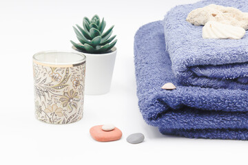 set consisting of blue towel with candle plant and stones.