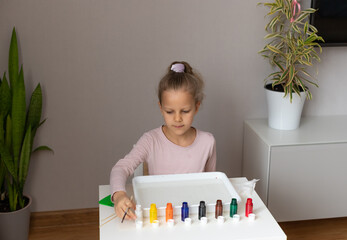 preschooler girl starts drawing in the ebru technique, sitting at the table at home. Ebru painting