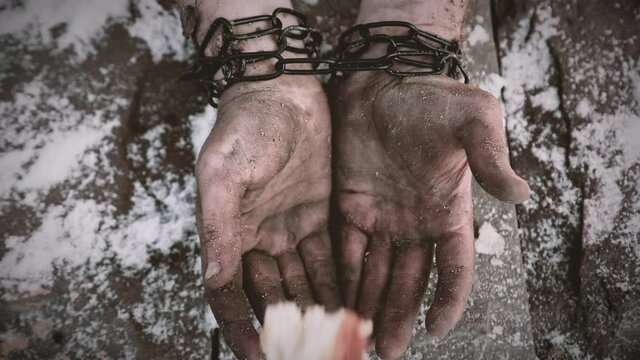 slave holds bread in his hands. slave in chains. bread in dirty hands. poverty, misery. bread in the hands of a slave. chained slave