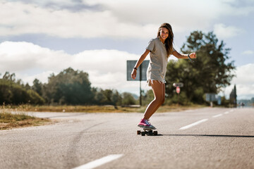 Young sporty woman riding on the skateboard on the road.