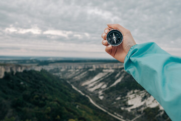 Compass in hand. Travel symbol. Against the background of nature. - 417125608