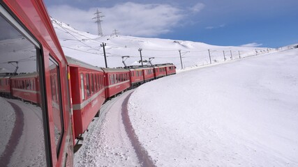 Europe, Switzerland Alps , Poschiavo February 2021 - Live shot from the window  of the  Bernina Express, red train  pass in Ospizio Bernina station -  White lake ( lago bianco ) frozen 