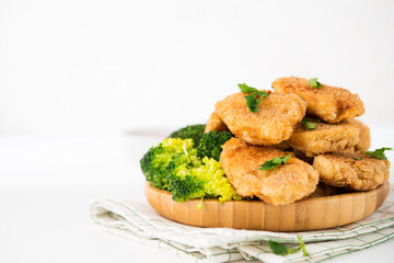 Homemade chicken nuggets with vegetables (broccoli) in a plate on a white background,