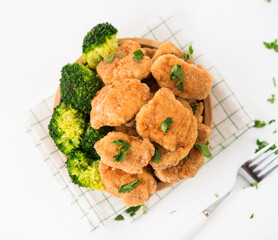 Homemade chicken nuggets with vegetables (broccoli) in a plate on a white background, selective focus