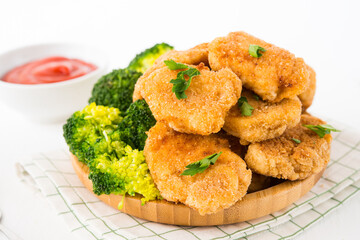 Homemade chicken nuggets with vegetables (broccoli) in a plate on a white background, selective focus