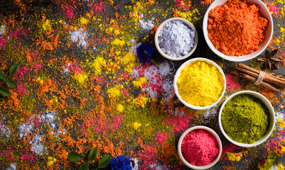 Holi festival celebration. Traditional Indian Holi colours powder decoration with paints. Top view of Organic Gulal colors in bowls ondark background.