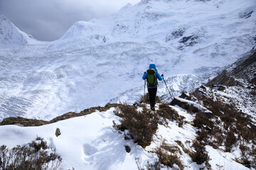 Successful woman backpacker hiking in winter mountains