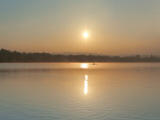 The beautiful landscape of Lake Baldeneysee just after sunrise with the rowers in the background.