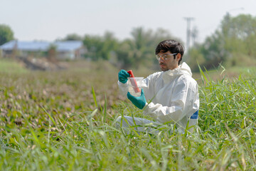 A man in full body protective suit collecting samples of water potentially contaminated by toxic material ,water quality monitoring concept ,ph checking on field.