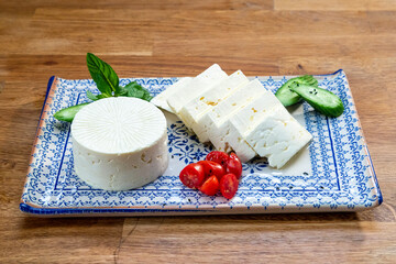 Sliced Feta cheese with tomato, herbs and olive oil.