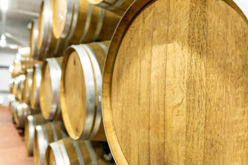 Selective focus. Row of Large French Oak Red Wine Barrels in a Modern Wine Warehouse