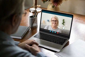 Happy 50s years old couple chatting via video call from home. Laptop screen view of middle aged woman talking to husband or father. Family speaking at webcam during remote virtual conference meeting
