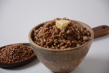 Bowl of tasty buckwheat porridge with piece of butter on the top