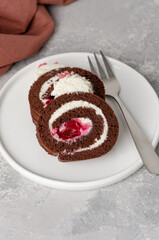 Black forest chocolate cake roll with whipped cream and cherry filling on a gray background. Copy space.