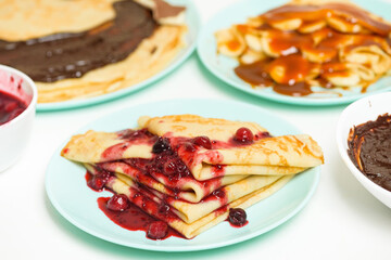 blini pancakes with red berry jam close-up on a blue plate on a light background . traditional...