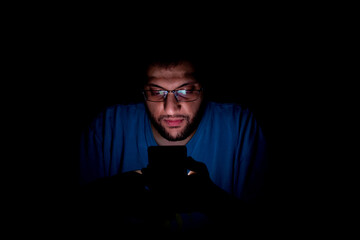 Portrait of middle eastern guy checking his phone in a dark room
