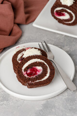 Black forest chocolate cake roll with whipped cream and cherry filling on a gray background. Copy space.