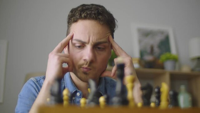 A young handsome guy is thinking about the next move in a difficult game