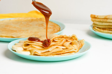 blini pancakes with caramel, dripping on a spoon levitation close-up on a blue plate on a light background . traditional Russian holiday is a symbol of spring and sweet dessert