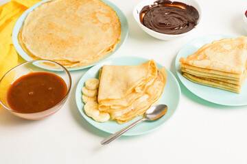 blini pancakes with banana and caramel, close-up on a blue plate on a light background ....
